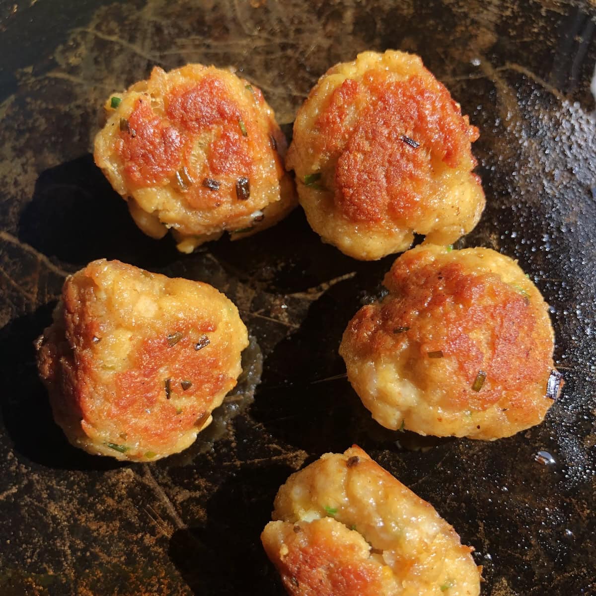 Crispy golden brown pan seared chicken and pork meatballs fully cooked in a cast iron skillet for easy meatball recipe.