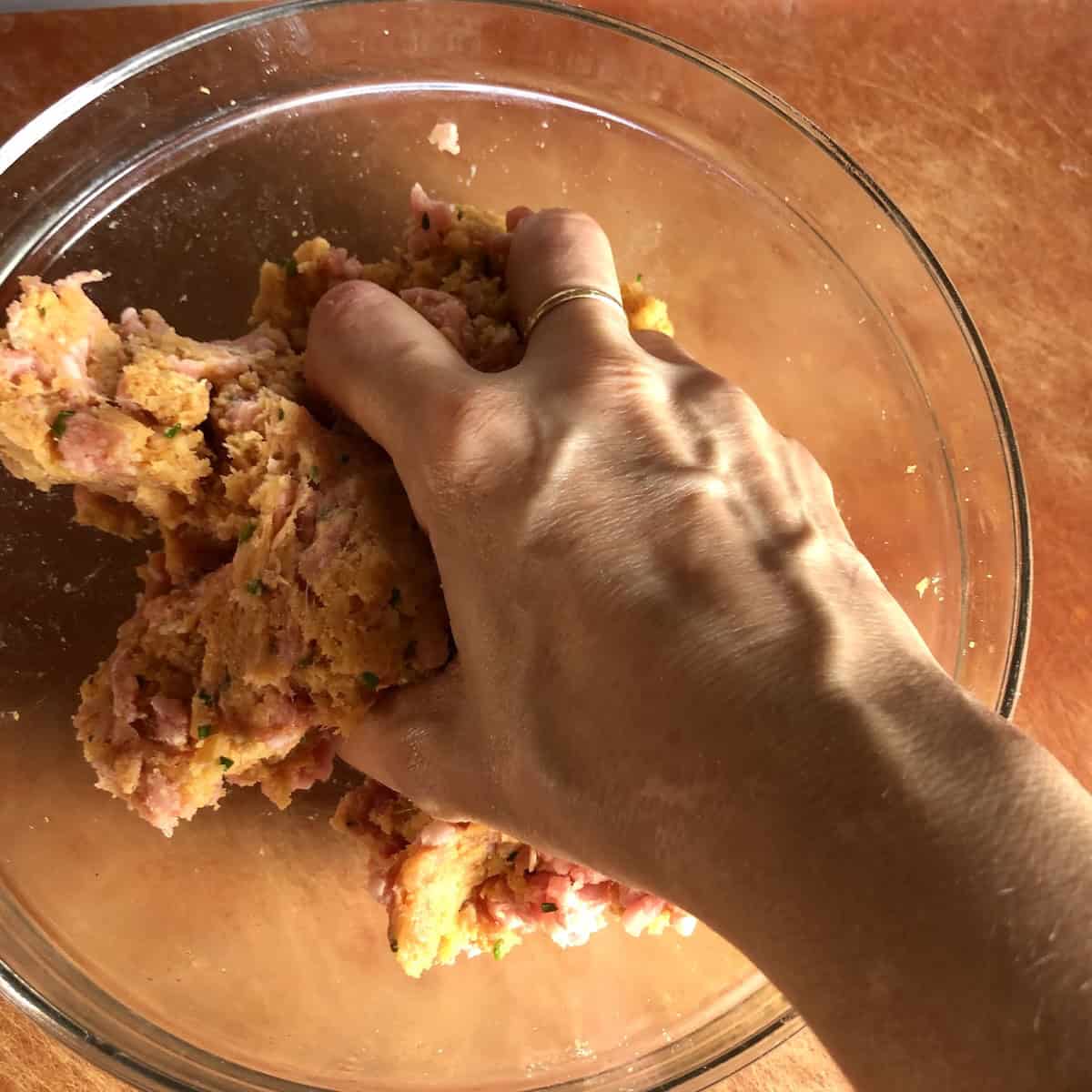 Adding ground pork to the chicken meatball mixture and mixing by hand for tender juicy baked meatballs.