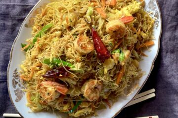 an oval platter of Singapore Mei Fun noodles with shrimp, carrots, cabbage, scallions