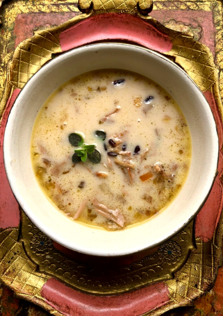 a bowl of warm and slightly creamy turkey and wild rice soup on a vintage pink and gold venetian serving tray