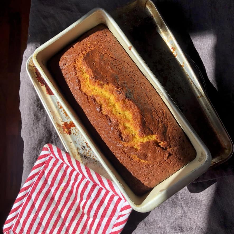 A fully baked loaf of pumpkin walnut bread just after it's been removed from the oven. 
