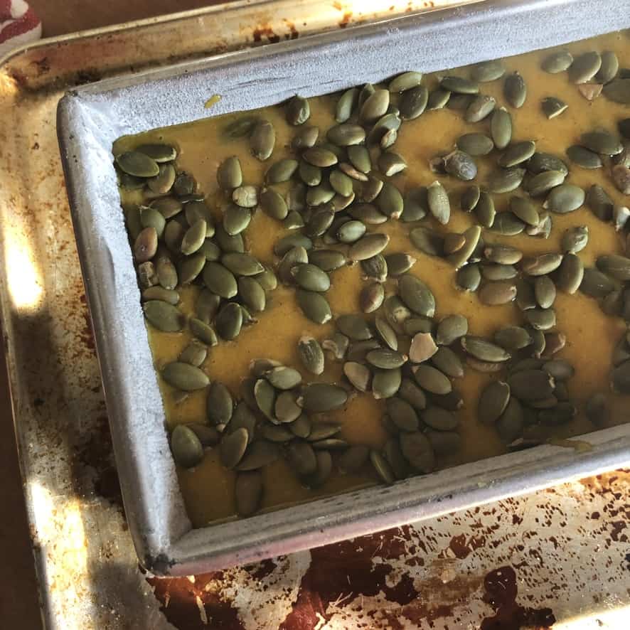 Pumpkin bread batter topped off with even more toatsed pumpkin seeds.
