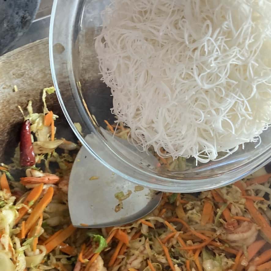 adding the noodles to the wok