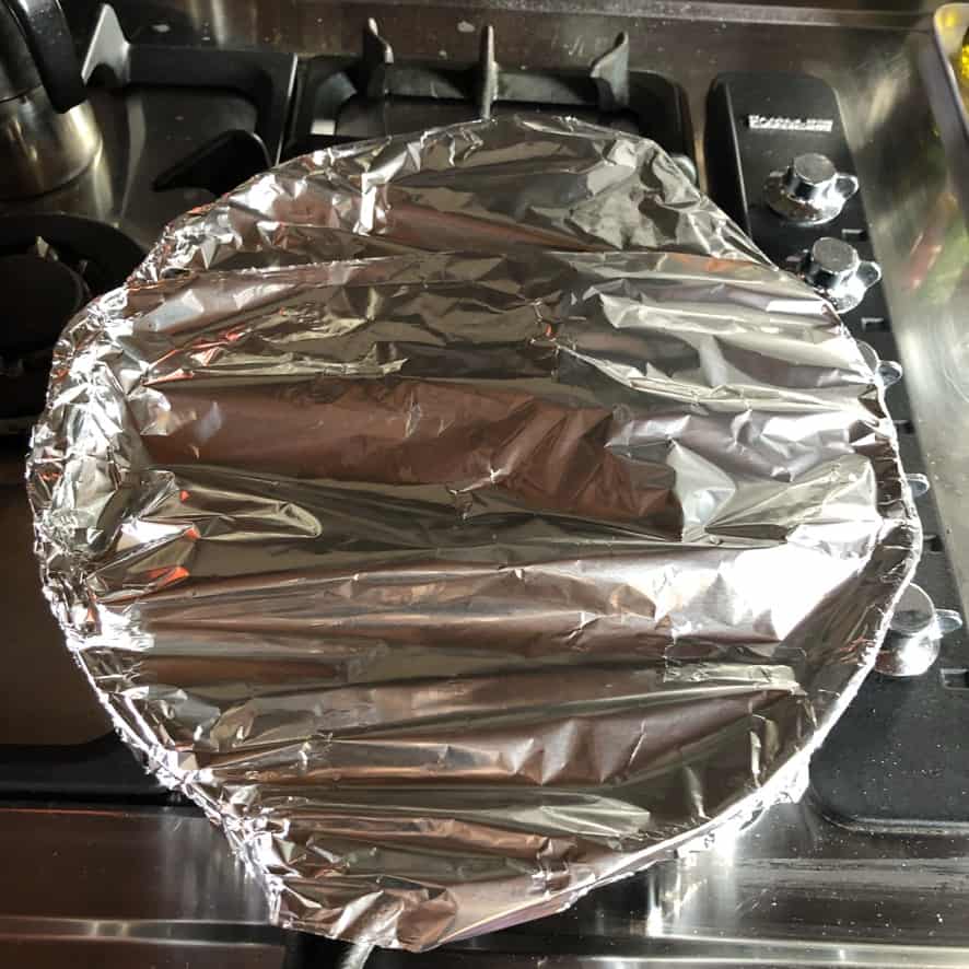 a cast iron skillet covered with aluminum foil ready to put in the oven
