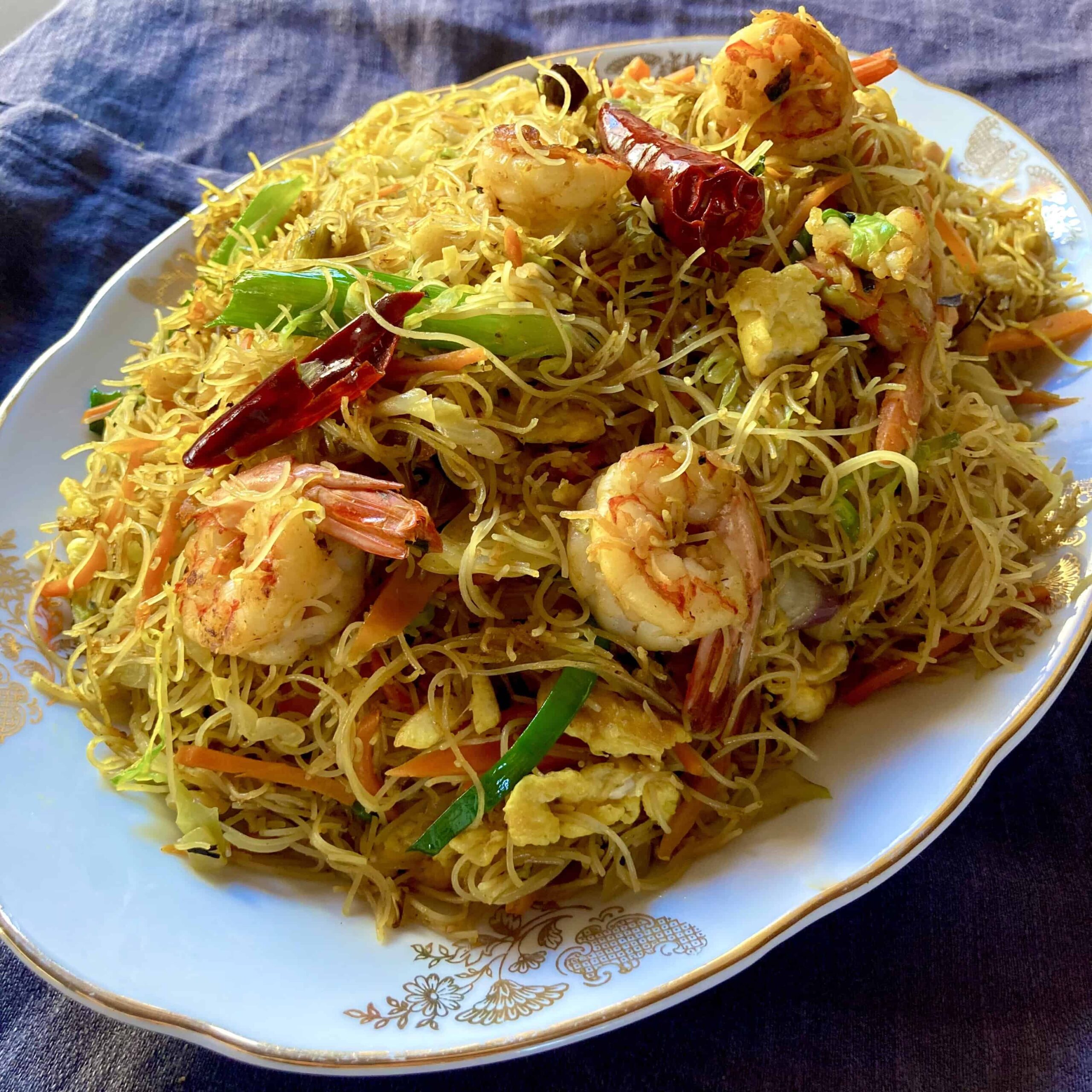 an oval platter of Singapore Mei Fun noodles with shrimp, carrots, cabbage, scallions