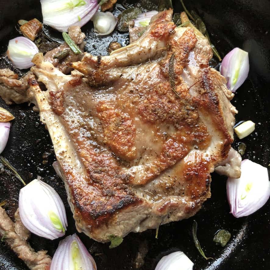 perfectly golden brown crispy skinned seared turkey in a skillet with shallots and herbs