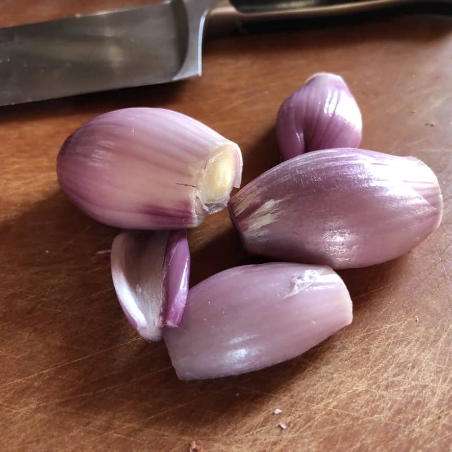 four peeled shallots on a cutting board
