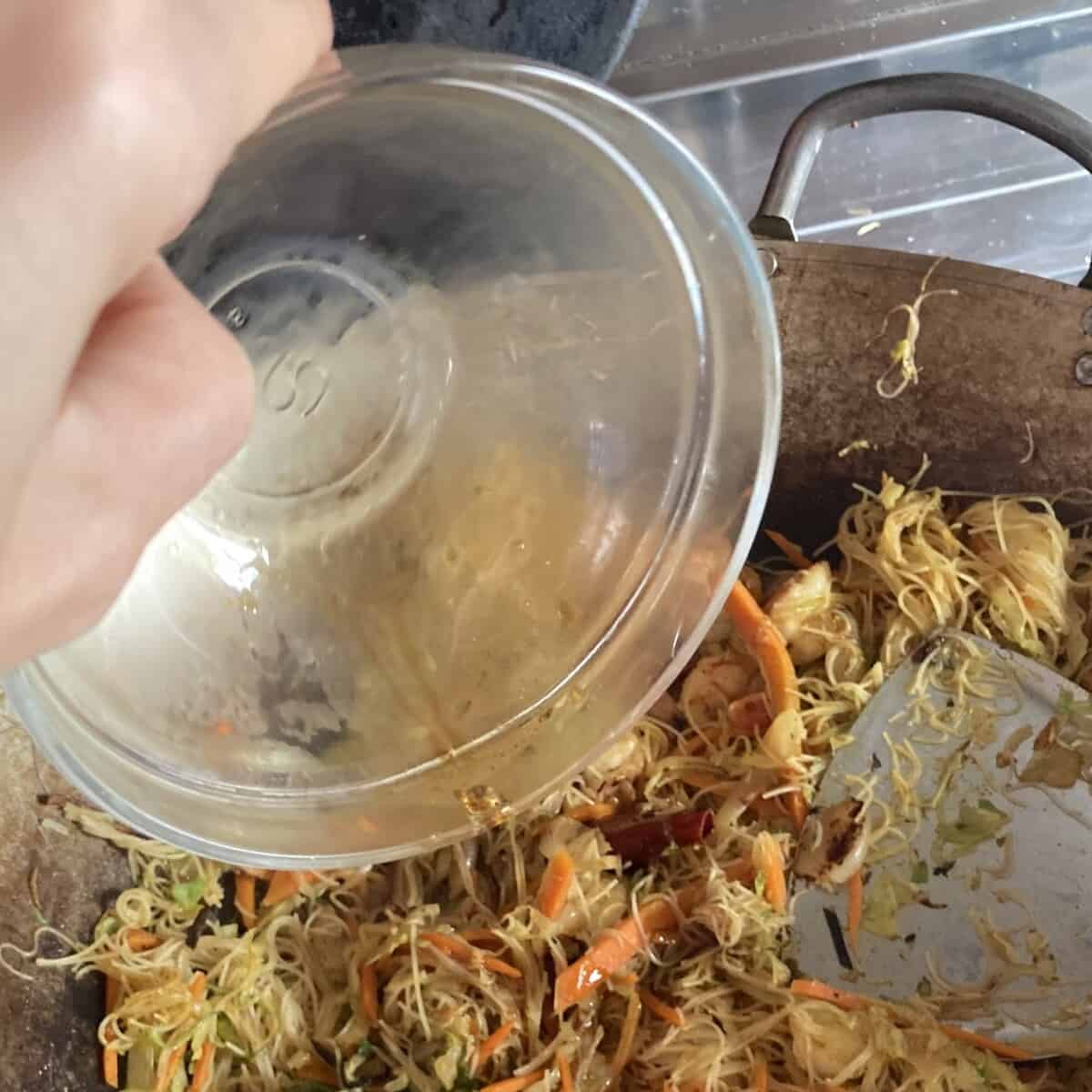 adding the wet sauce ingredients to the wok