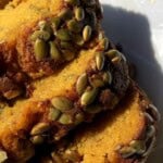 Slices of super moist pumpkin bread with toasted pumpkin seed topping.