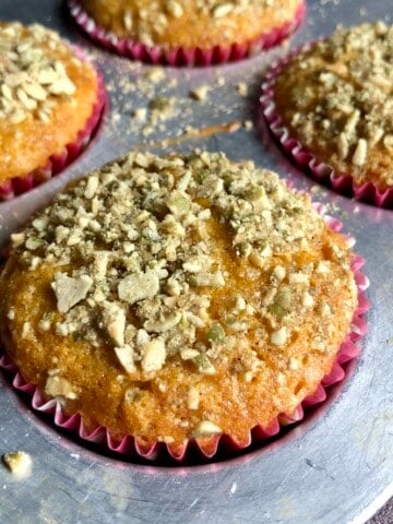 Golden domed pumpkin muffins with pumpkin seed crunch topping in the muffin tin, best pumpkin muffins from scratch.