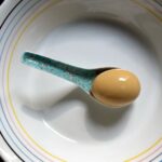 a single mirin-soy stained soft boiled egg in a ramen spoon