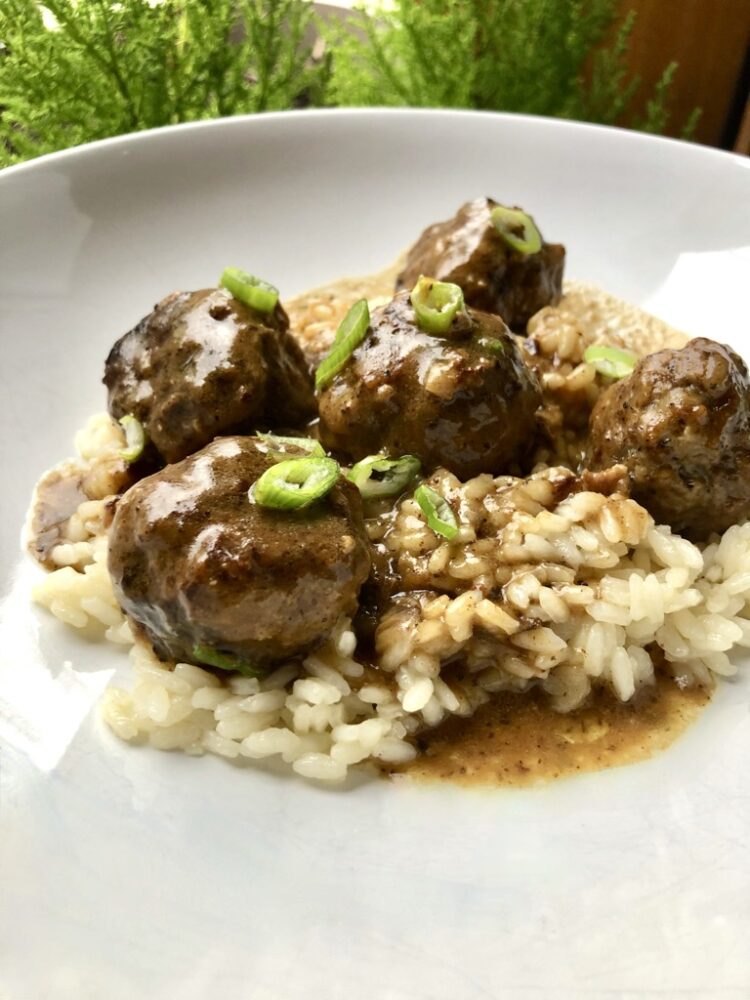 swedish meatballs smothered in a pan gravy on top of a bed of white rice