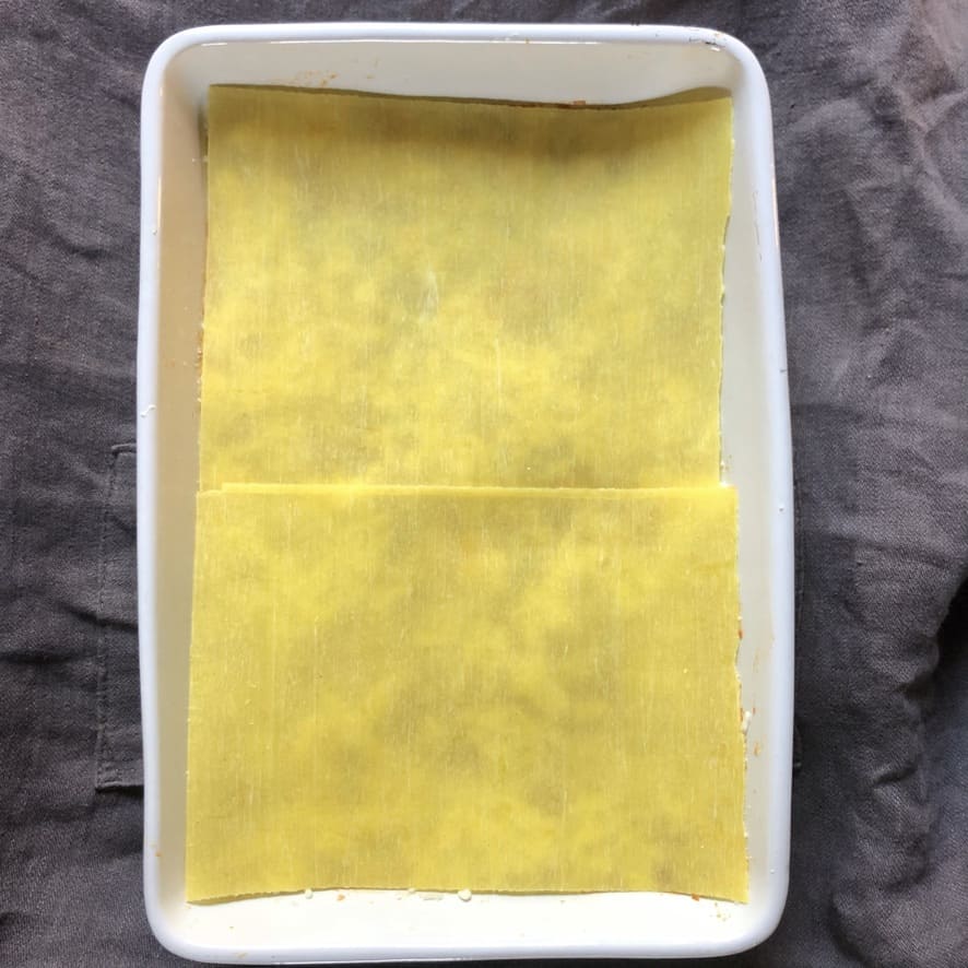 adding fresh lasagna sheets to cover the ragù