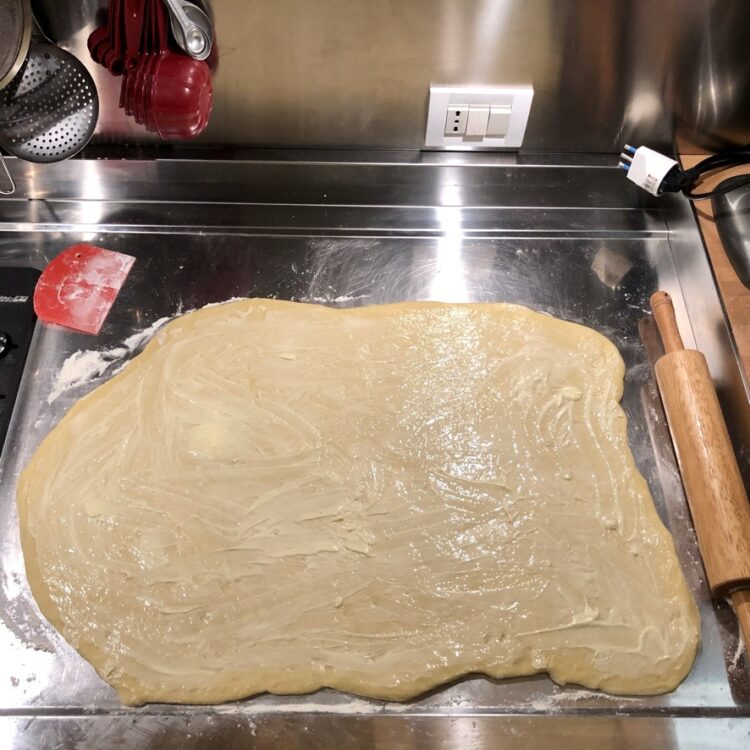 cinnamon roll dough rolled out into a rectangle with butter smeared all over