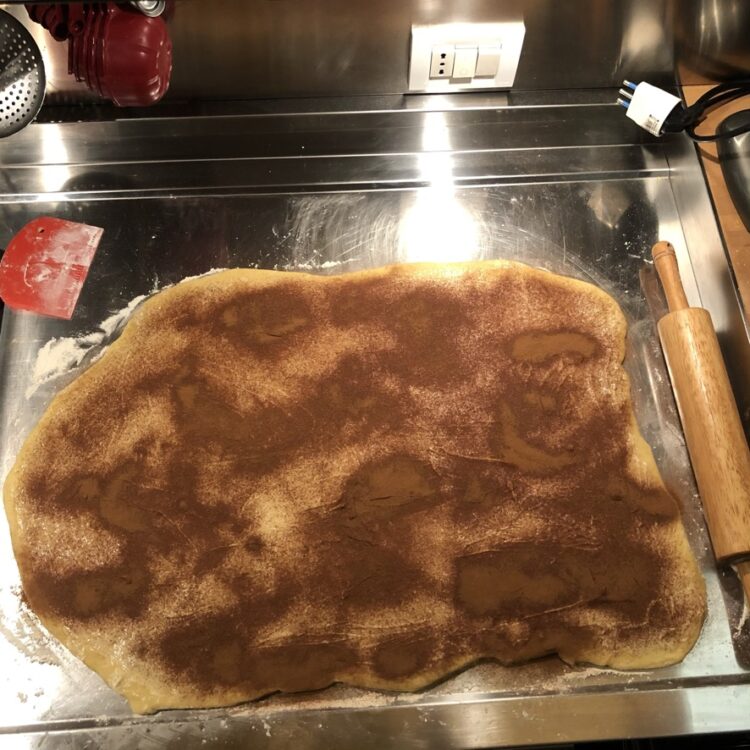 cinnamon roll dough rolled out into a rectangle with butter and cinnamon added