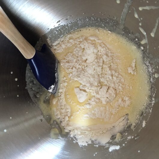 1/2 of the flour mixture being added to the egg-sugar mixture