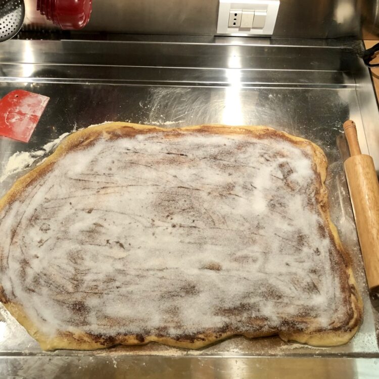 cinnamon roll dough rolled out into a rectangle with butter, sugar and cinnamon added