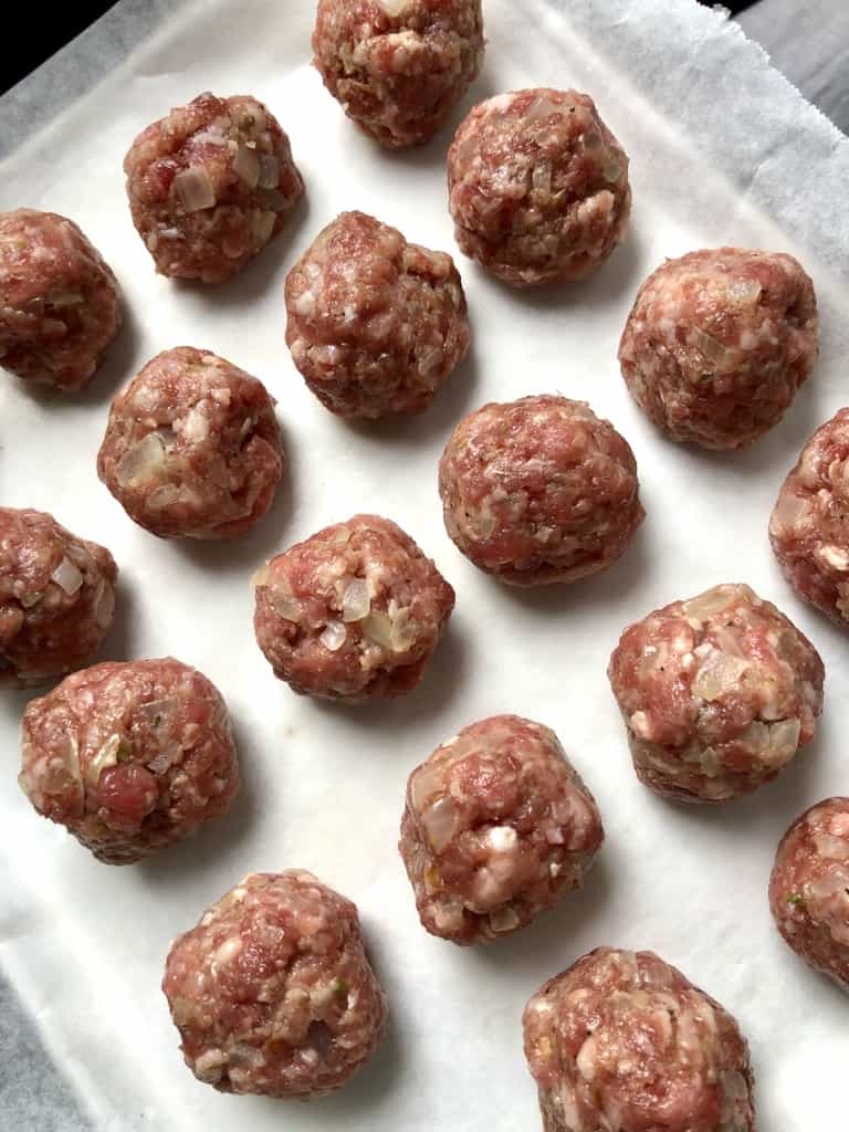 raw swedish meatballs on a parchment lined baking tray