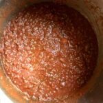 bright red La Giara Tomato Passata added to the beef and white wine mixture after being stirred together