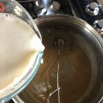 pouring the hot porcini and onion infused milk into the roux to create the bechamel sauce