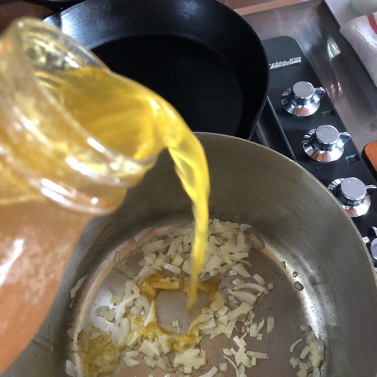 adding chicken broth to the pot with onions