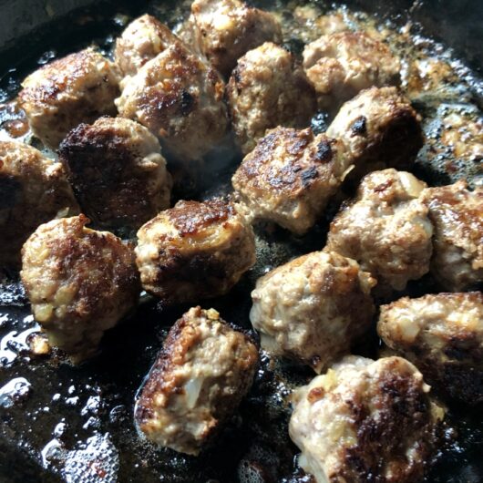 deeply browned meatballs in a cast iron skillet