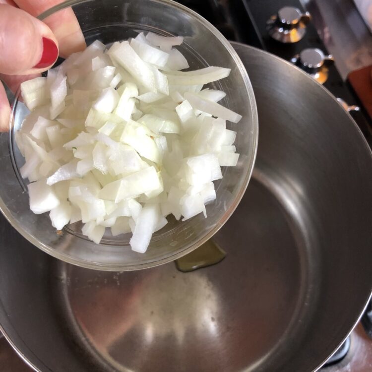 adding chopped onions to the soup pot