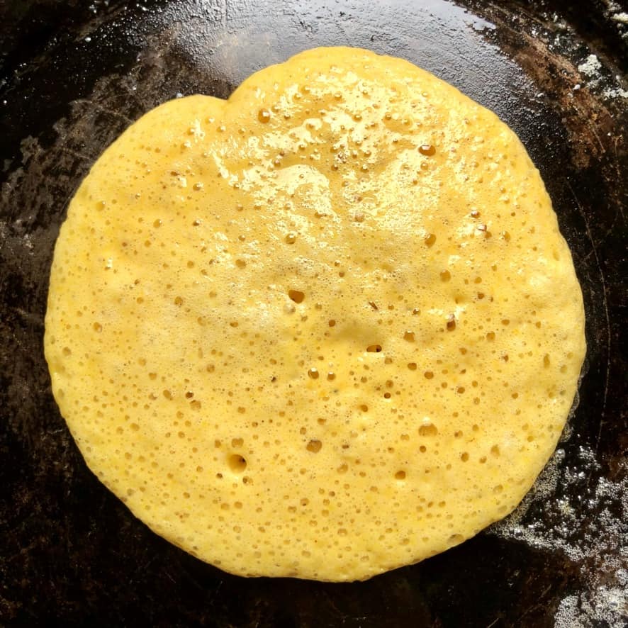 pumpkin pancake cooking in a crêpe pan with bubbles