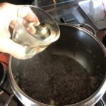 pouring white wine into the pot with ground beef