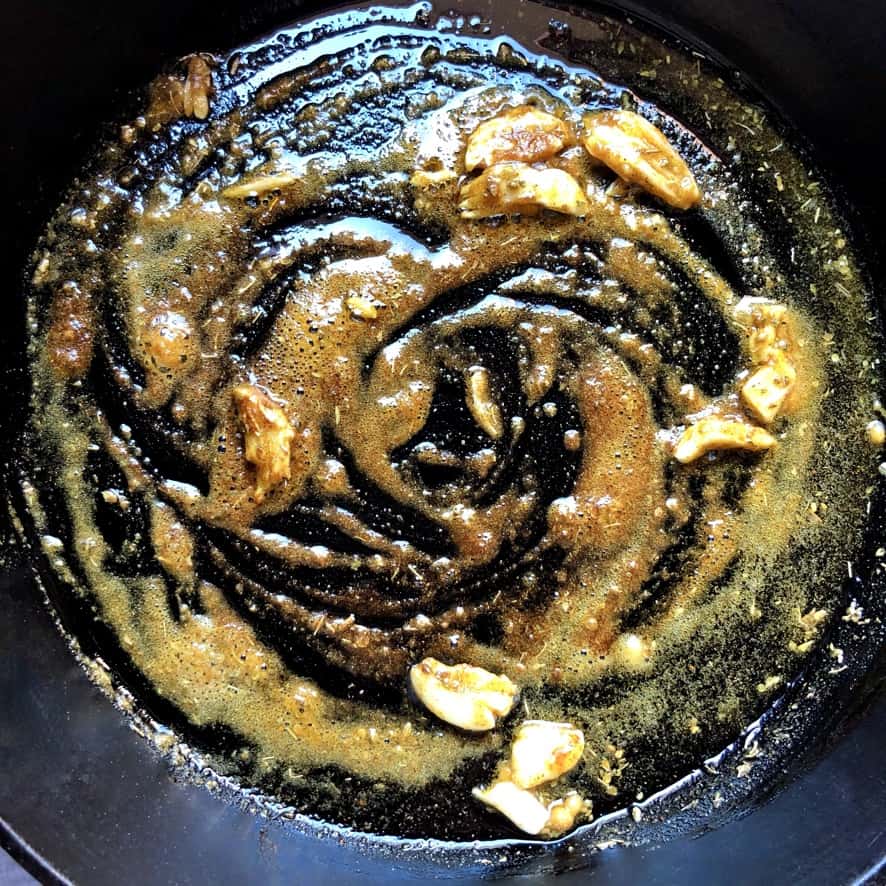 toasting spices with garlic and oil in a cast iron skillet