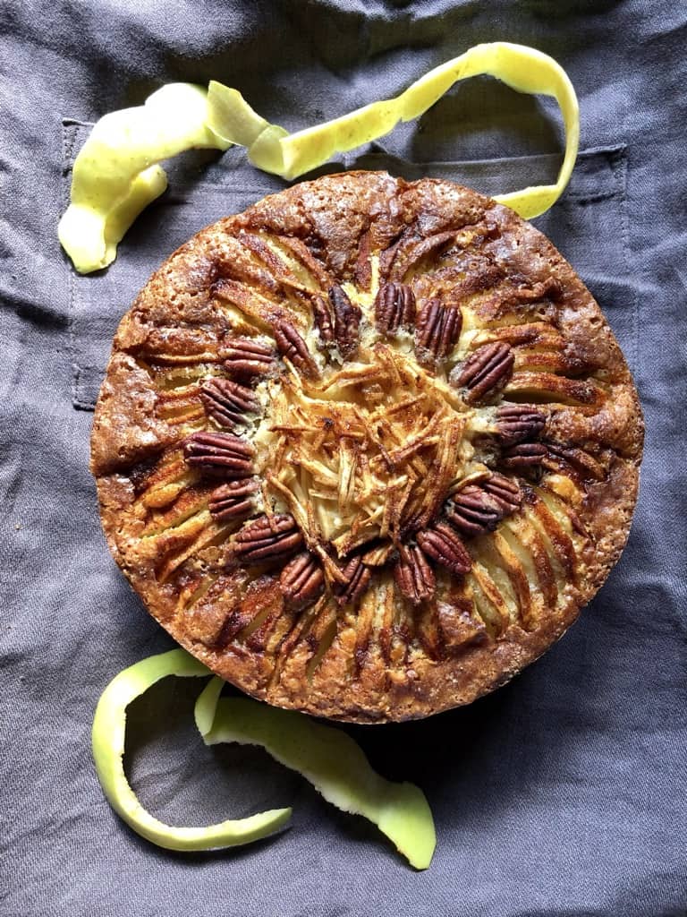 a whole apple cake with golden yellow apple peels around the top and bottom of the cake