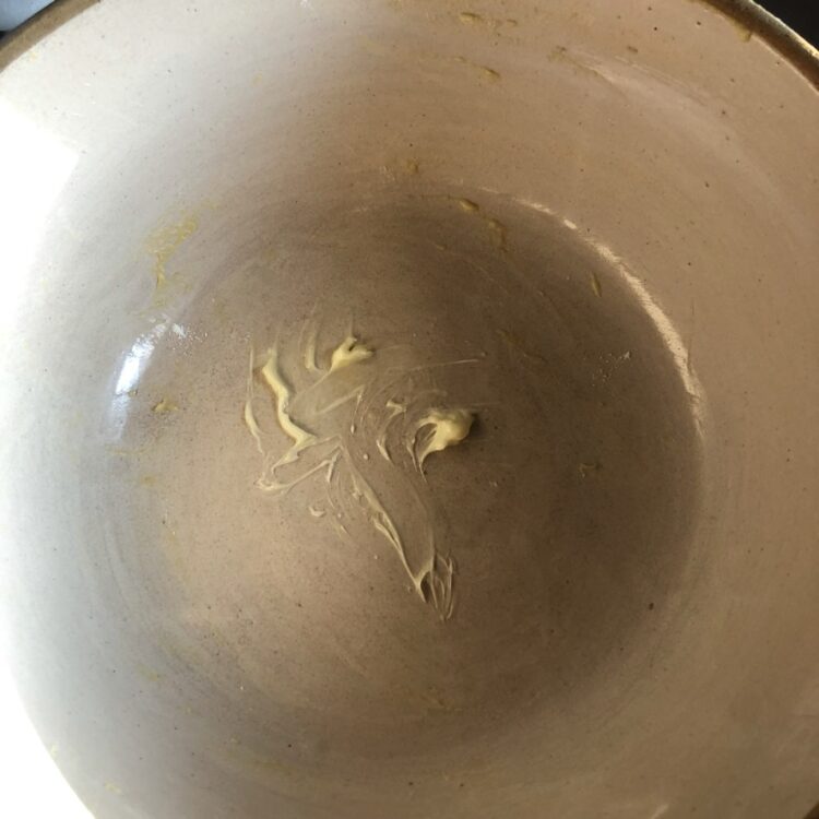 smearing butter inside the bowl to place dough in to rise