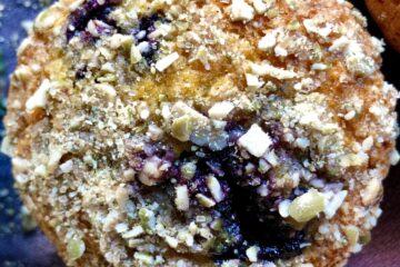closeup of a bluerry pumpkin muffin with toasted pumpkin seed crunch baked on top.