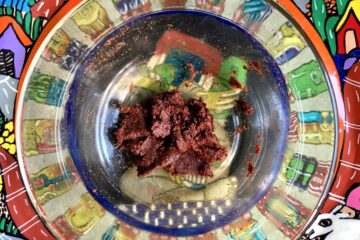 homemade chipotle in adobo sauce just mixed in a glass bowl sitting on top of a brightly painted terra cotta Mexican artwork plate
