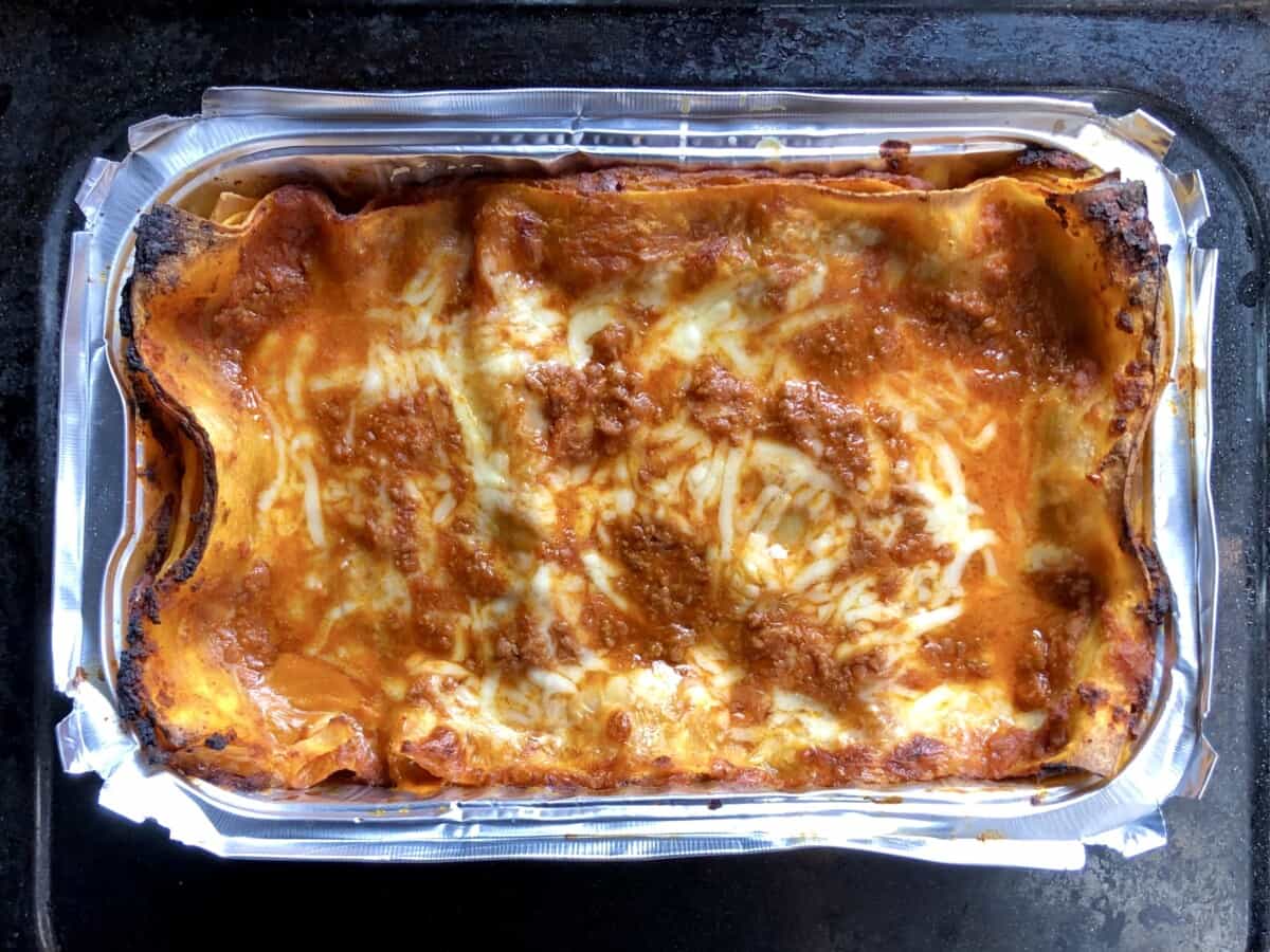 a rectangular foil baking dish filled with melty, tomatoey lasagna