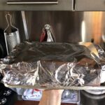 lasagna al ragù covered with aluminum foil and ready to be baked
