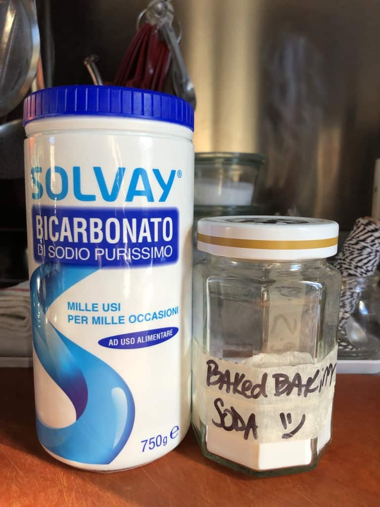 a large plastic container of Italian baking soda next to a homemade baked baking soda (sodium carbonate) on a cutting board