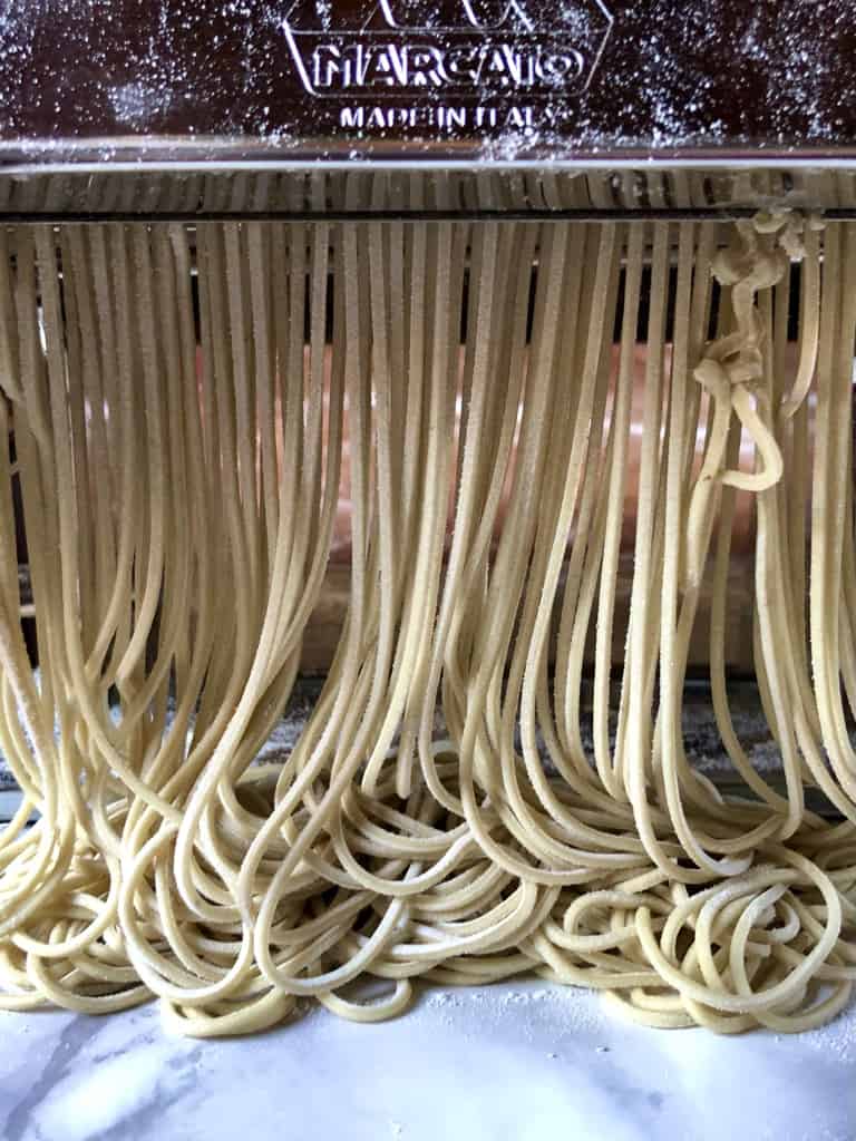 homemade ramen noodles being rolled and cut in a pasta machine