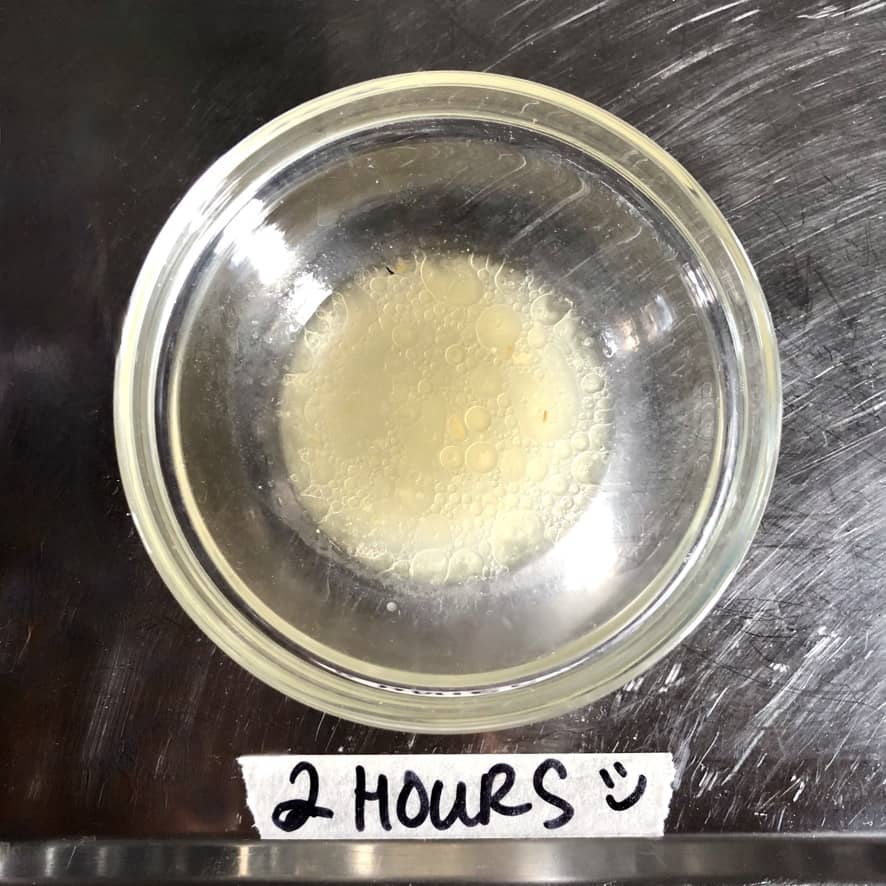 Tonkotsu ramen broth after 2 hours of cooking the broth looking beige in color, like a cloudier chicken broth, and fat globules suspended on top.