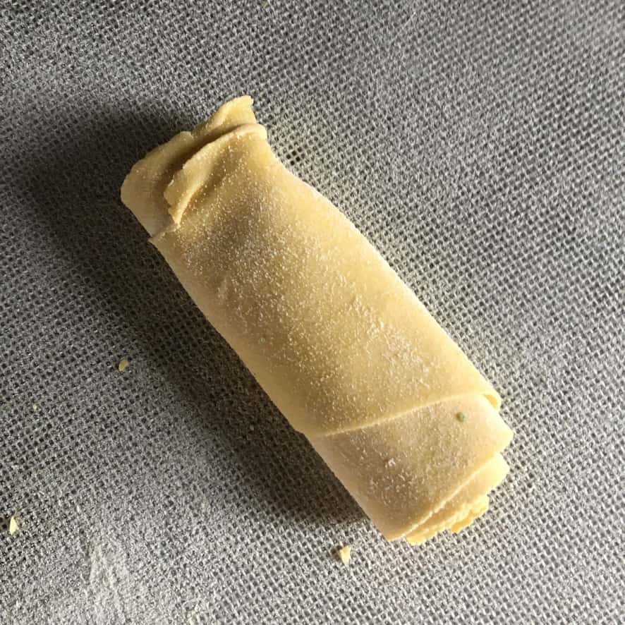 a rolled up sheet of pasta ready to be cut into desired width noodles