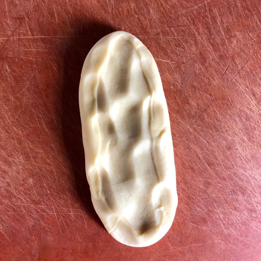 a dough piece pressed down into a long rectangular piece to make it easier to put through the pasta machine to roll it