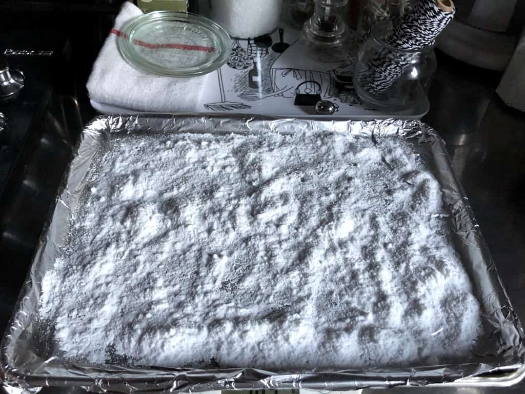 an aluminum foil-covered sheet pan with baking soda spread out evenly over the entire top