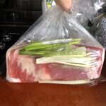twisting up a bag with pork belly and the brining liquid so the meat is fully covered