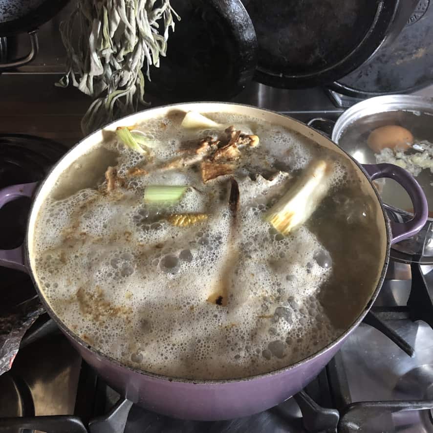 tonkotsu broth boiling away in a dutch oven with the skum rising to the top