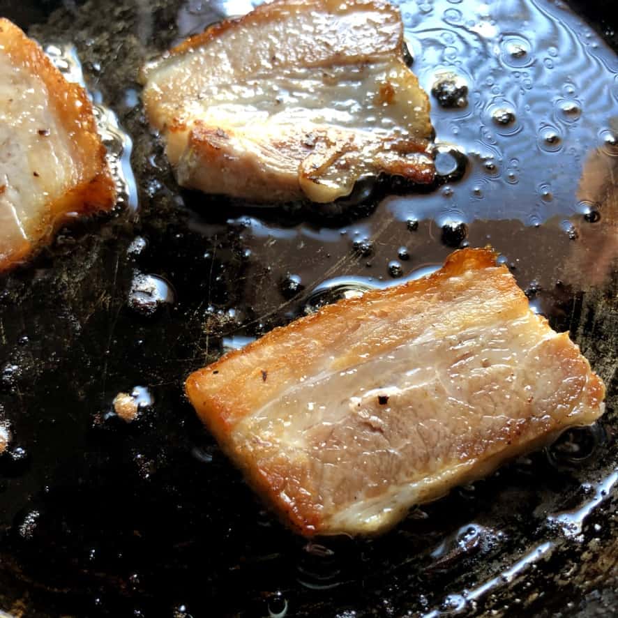 braised pork belly being pan seared