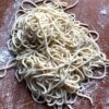 raw homemade ramen noodles on a cutting board that have been dusted with flour and nested