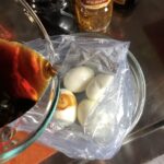 ramen egg marinade being poured over soft boiled eggs in a plastic bag