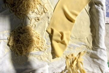 traditional homemade egg noodles being dried (some are traditional egg noodle shape for chicken soup and others are curly and look like ramen noodlees)