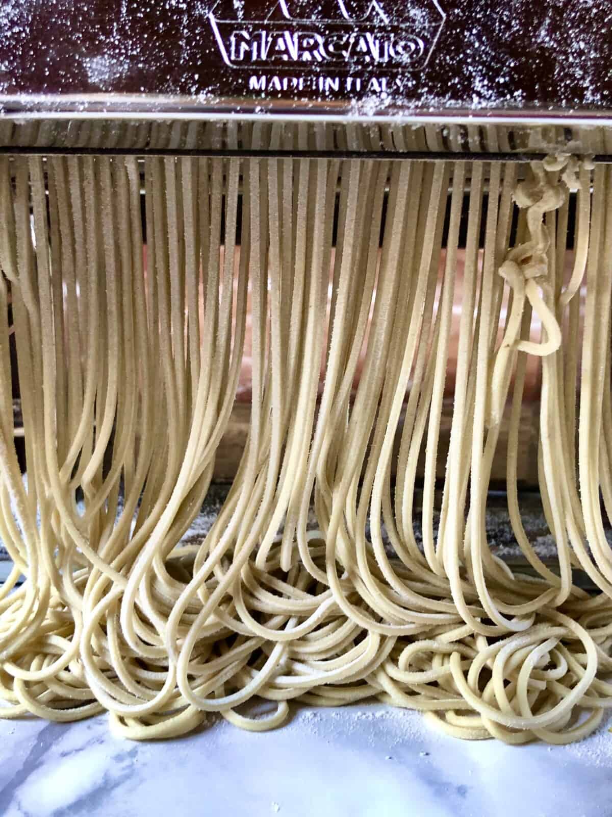 ramen noodles being cut in a pasta machine