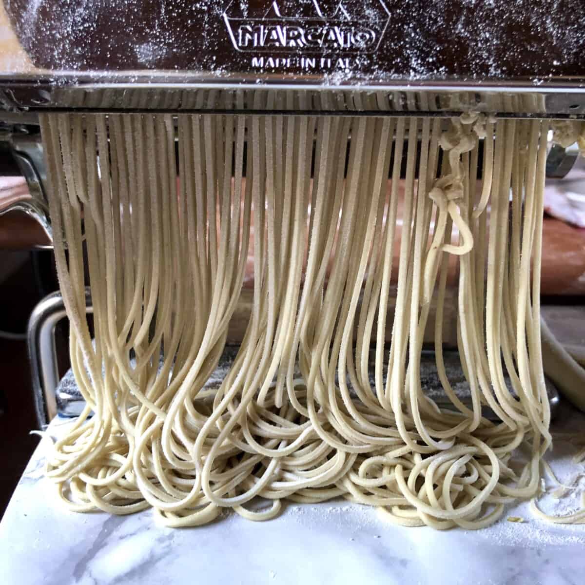 homemade alkaline ramen noodles being cut using a pasta machine